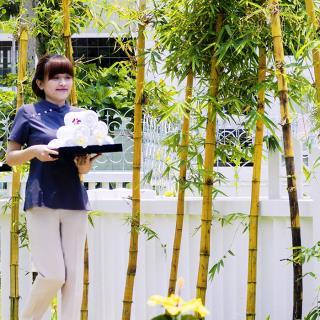 Two employees carrying trays near bamboos sticks.