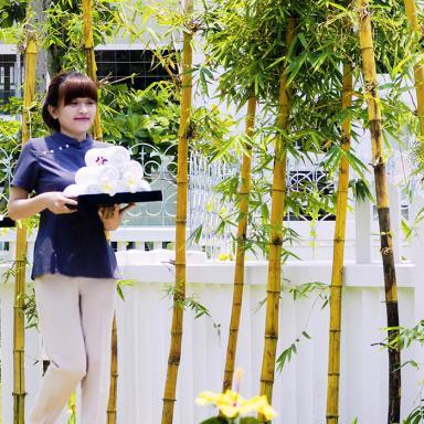 Two employees carrying trays near bamboos sticks.