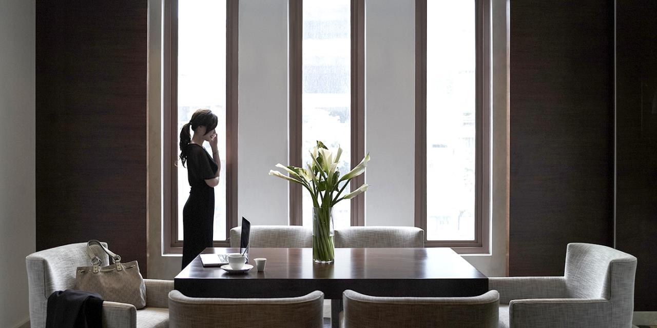 une femme business salle de réunion devant 3 fenêtre haute travaille sur ordinateur