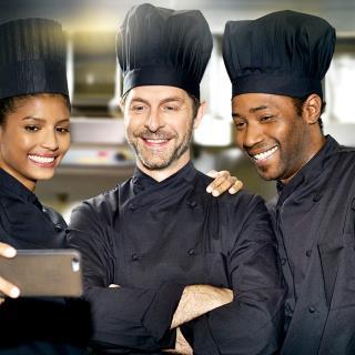 Three employees chef kitchen smiling taking together selfie on smartphone
