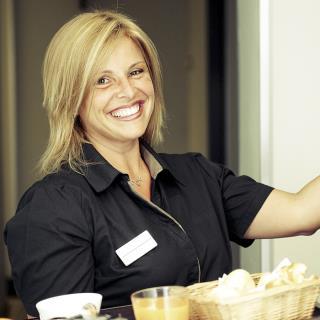 Woman employee knocking on door room hotel smiling holding breakfast tray